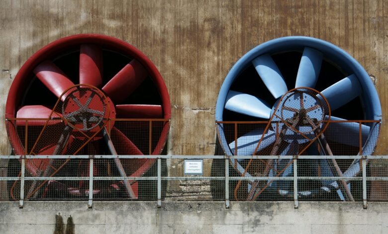 Close-up of large red and blue industrial fans on a rustic wall showcasing machinery and ventilation.